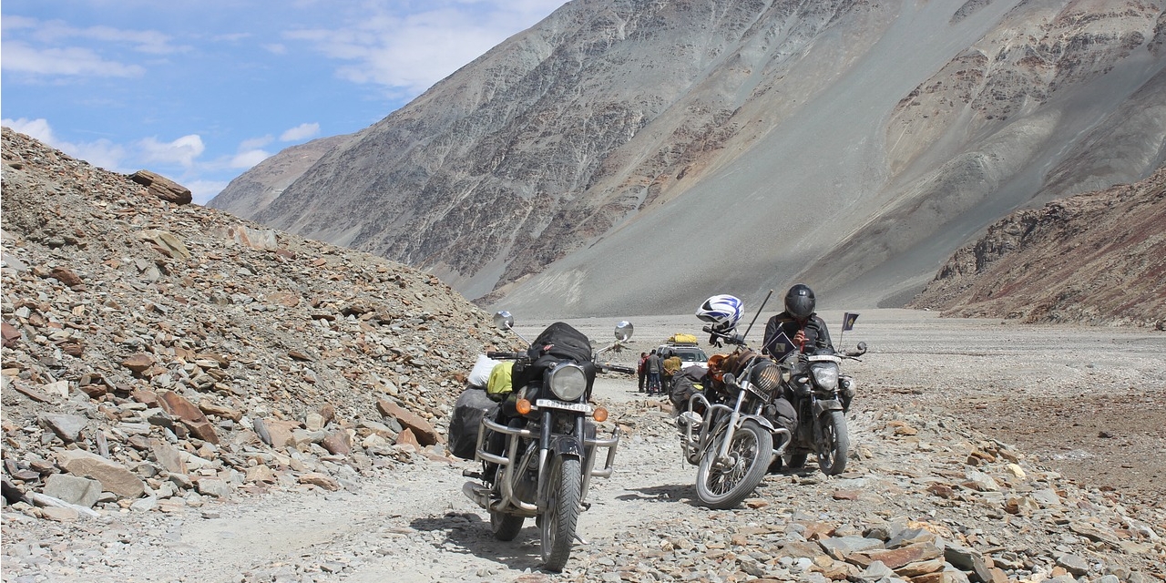 A wide-angle view of Pangong Lake in Leh Ladakh with turquoise waters surrounded by rugged mountains.