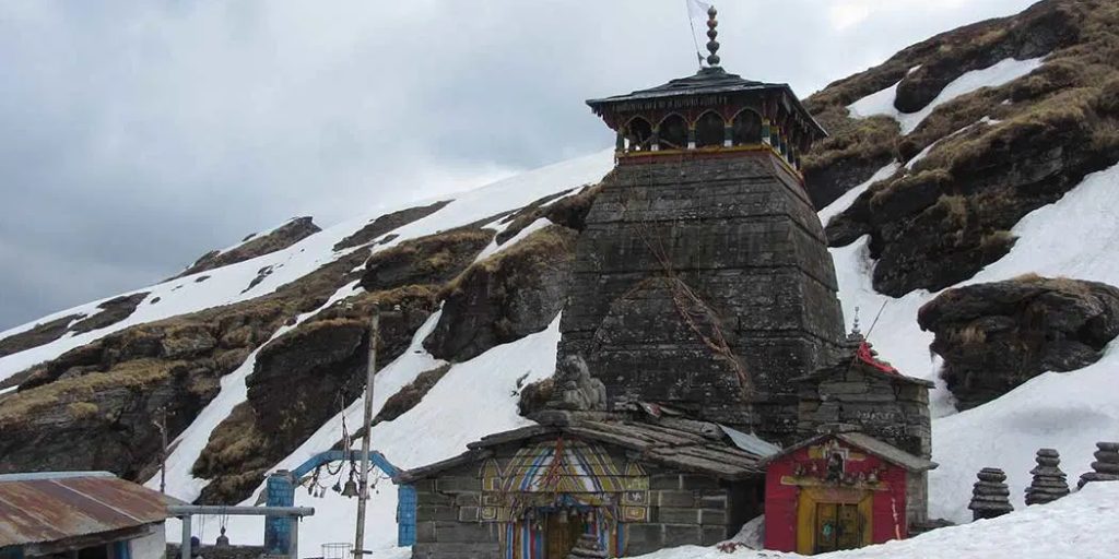"Snow-covered trail on Chopta Chandrashila Trek with view of Himalayan peaks and Tungnath Temple in Uttarakhand"