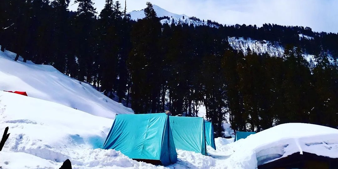"Trekkers walking on snow-covered trail during Kedarkantha Trek with view of Swargarohini range in Uttarakhand"